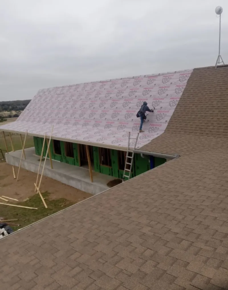 Worker preparing underlayment for a metal roof installation in Bullard